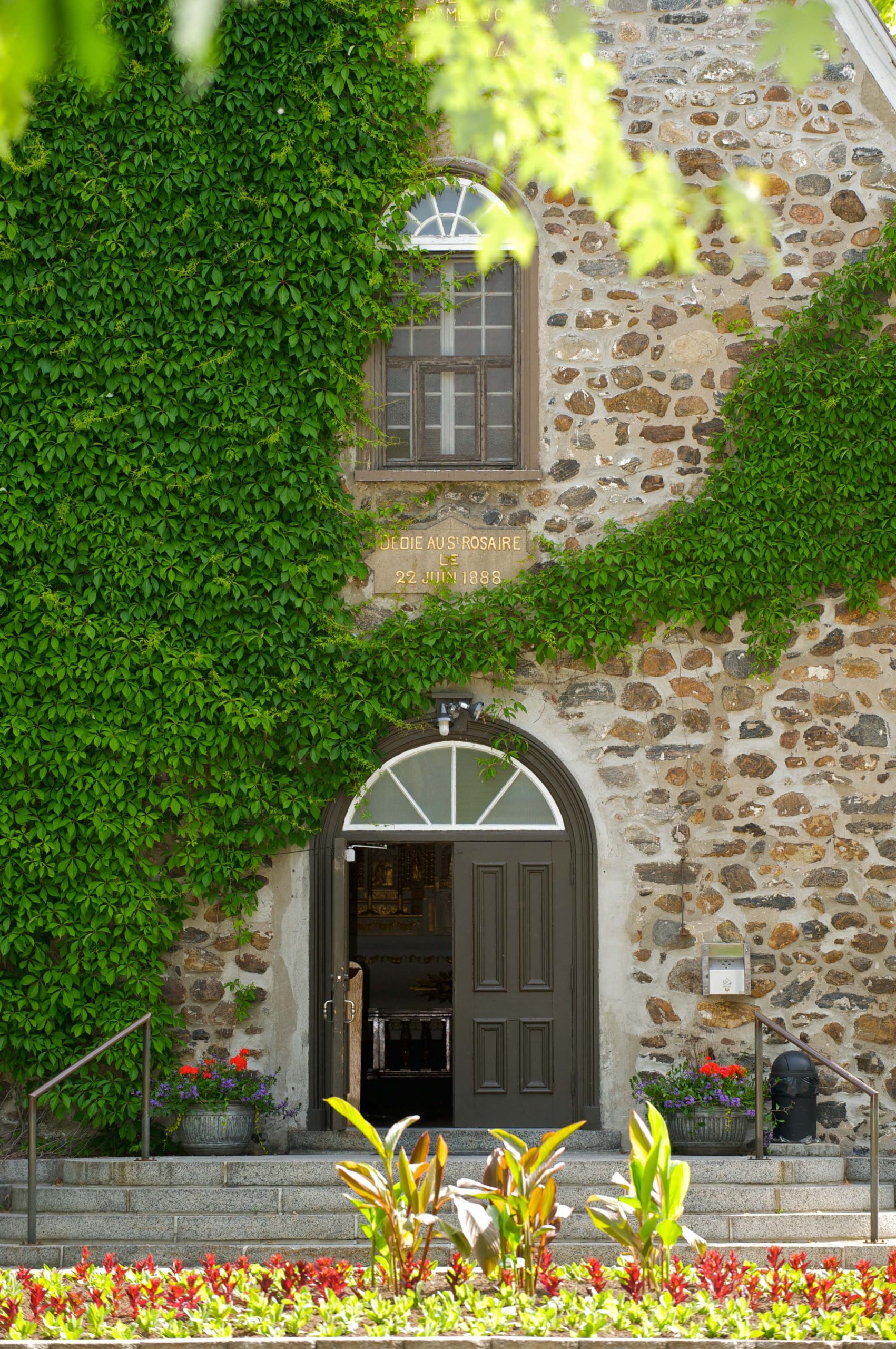 Photo de la façade extérieure du Sanctuaire Notre-Dame-du-Cap recouverte en partie de vigne